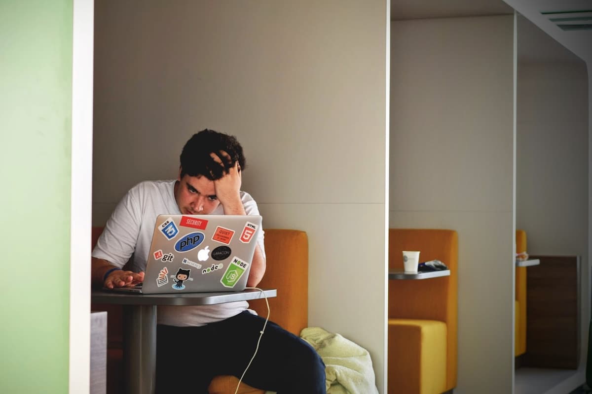 Frustrated developer holding head while looking at laptop