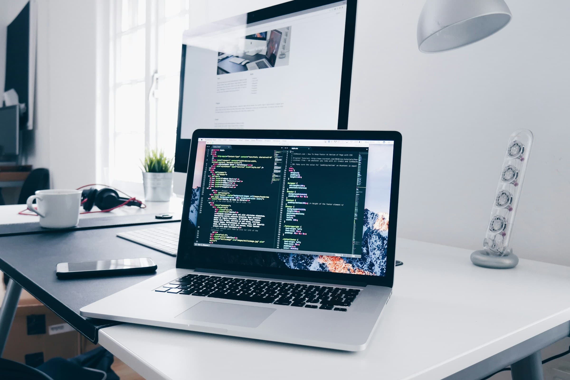 MacBook with code on a busy desk